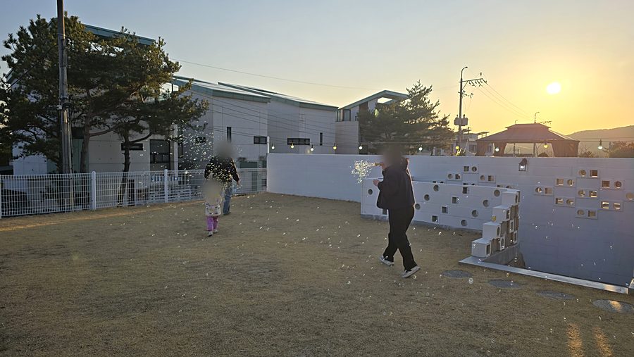 노을 지는 마당에서 뛰어노는 아이와 어른
